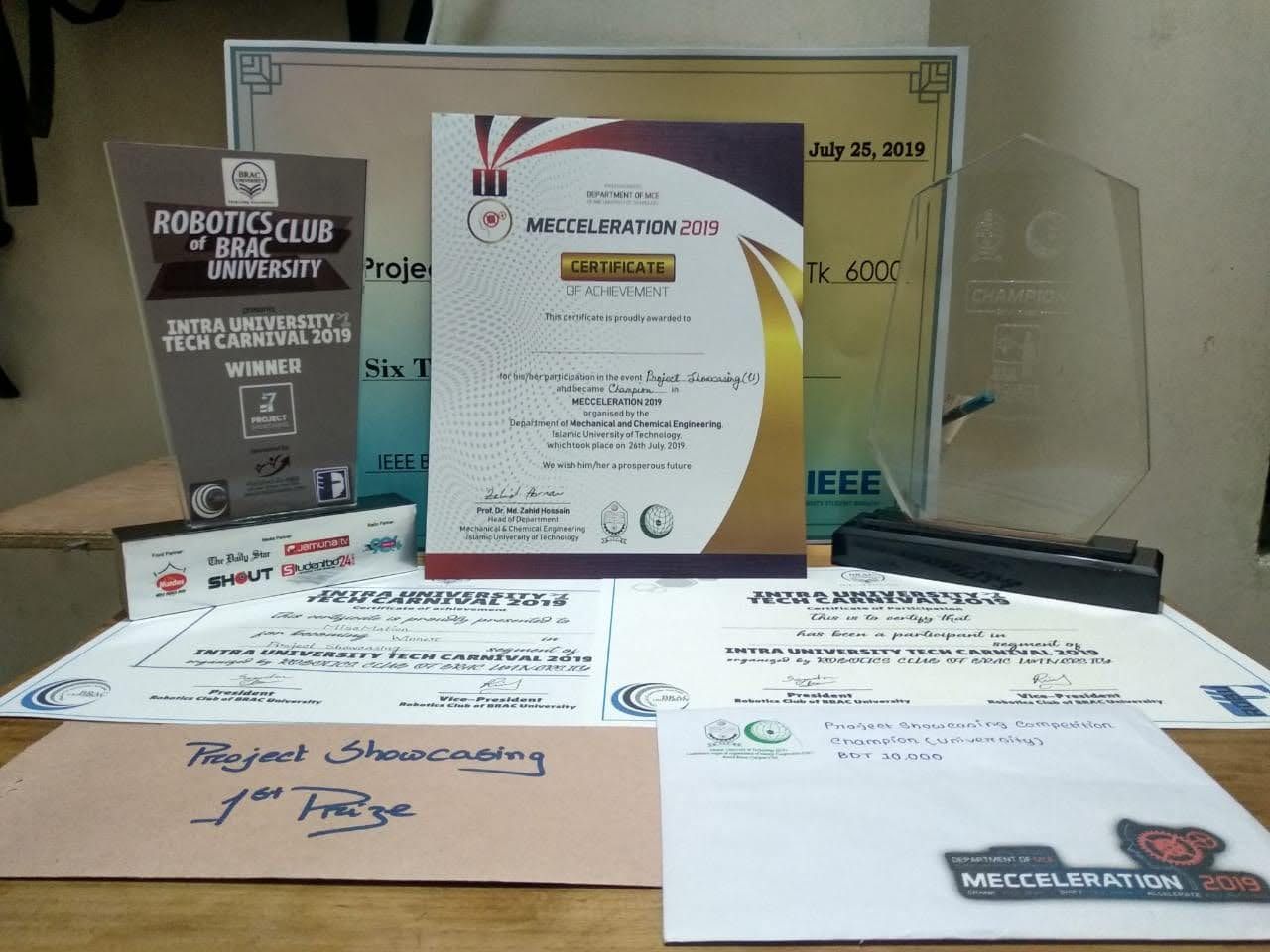 Trophies and certificates from the 2019 Intra University Tech Carnival and MECCELERATION laid out on a table.