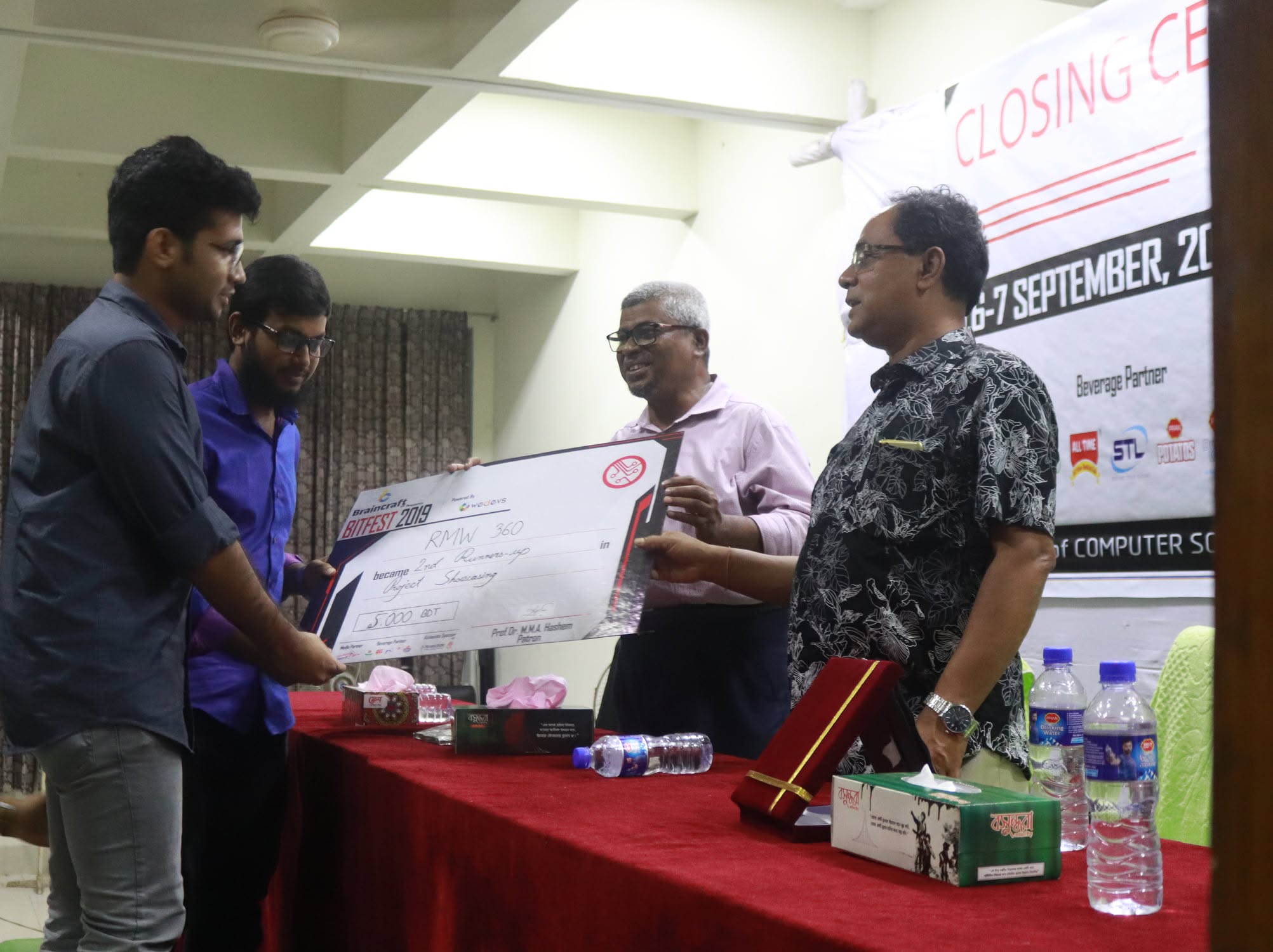Two students receiving the BitFest 2019 second runners-up cheque from a judge at the closing ceremony.
